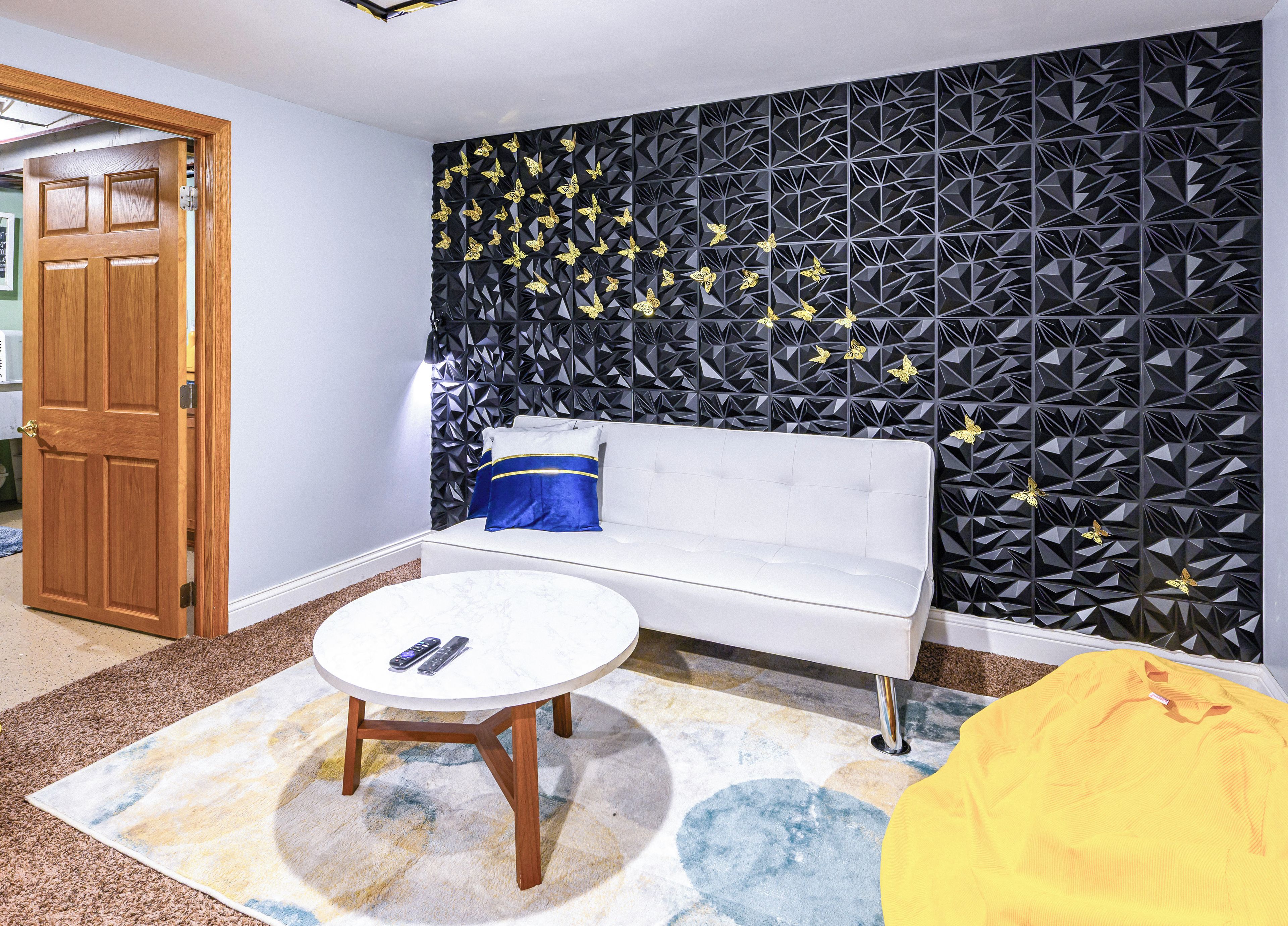 A room with a white sofa, a round coffee table, and a patterned wall.
