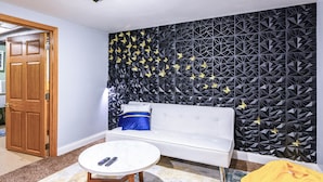 Una habitación con un sofá blanco, una mesita de centro redonda y una pared con diseño.