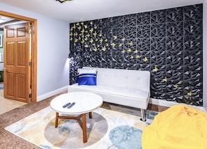 Quarto com sofá branco, mesa de centro redonda e parede estampada.