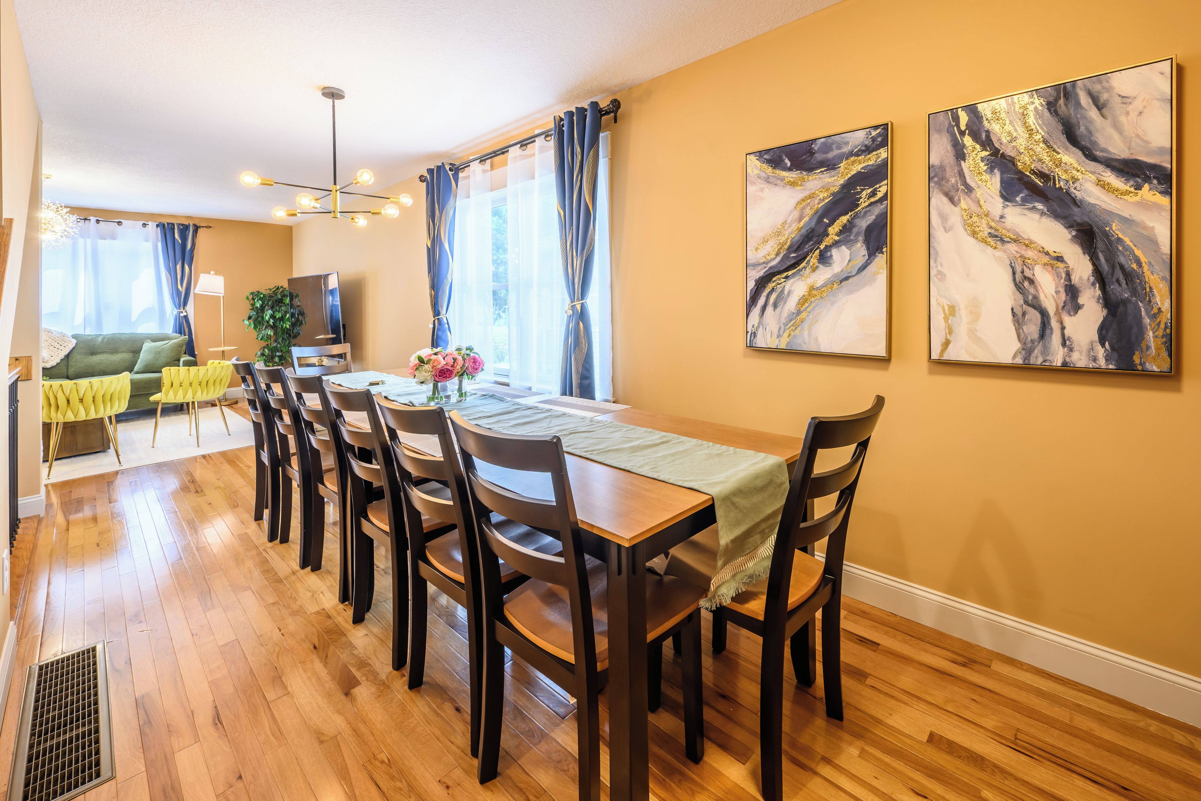 A dining area with a long table, multiple chairs, and a chandelier.