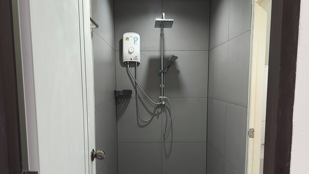 Un espace douche moderne doté d’un pommeau de douche à main et d’un panneau de commande fixé au mur.