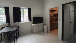 Un espace de vie compact comprenant un coin repas, une kitchenette et un téléviseur.