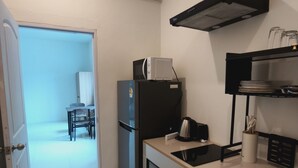 Une cuisine compacte équipée d’un four à micro-ondes, d’une bouilloire et d’une petite table à manger avec des chaises.