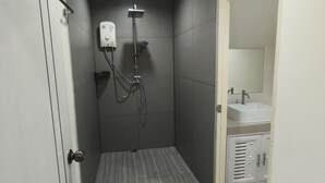 Une salle de bain avec une douche, un lavabo et un meuble de rangement.