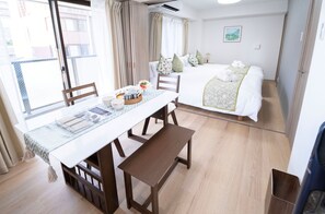 A hotel room with a bed, a dining table with chairs, a bench, and a view of the outside. - The Peak Dotonbori Suites (Dotonbori, Chuo-ku)