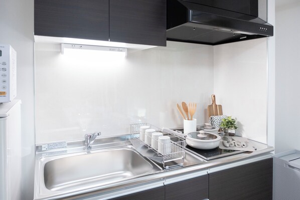 A modern kitchen with a stainless steel sink, a range hood, and a white backsplash. - The Peak Dotonbori Suites (Dotonbori, Chuo-ku)