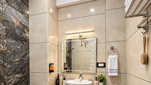 Un baño moderno con inodoro blanco, tocador de mármol y un espejo grande.