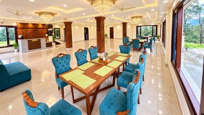 Un amplio vestíbulo de hotel con un amplio comedor, diversas opciones de asientos y una recepción.