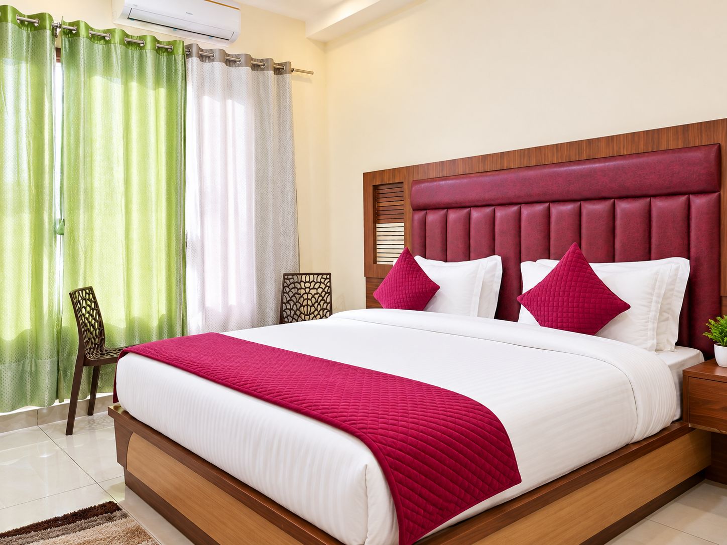 A hotel room with a large bed, a wooden headboard, and a green and white curtain.