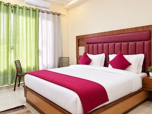 Una habitación de hotel con una cama grande, un cabecero de madera y una cortina verde y blanca.