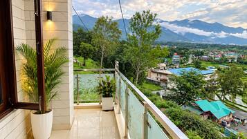 A balcony with a view of a mountainous landscape and a village below.