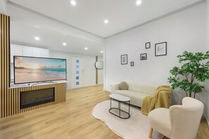 Una sala de estar moderna con una televisión de pantalla plana, un sofá, una mesa de centro y una mesita auxiliar.