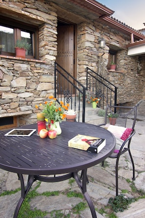 A stone house with a wooden door, a staircase, and a round table with a book and fruit. - Luxurious Country Home in Laroya (Laroya)