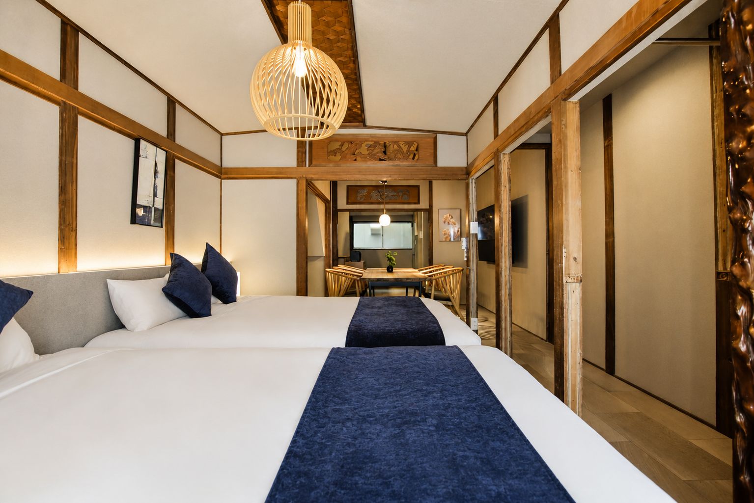 A hotel room with a large bed, a desk, and a dining area.