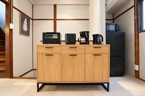 Eine Küche mit einem Holzkasten, einer Mikrowelle, einer Kaffeemaschine und einem Kühlschrank.