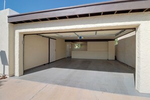 A covered parking area with a garage door, a concrete floor, and a clear sky. - Extended Stay Gem: Tucson Townhome, Pool + Tennis (Tucson)