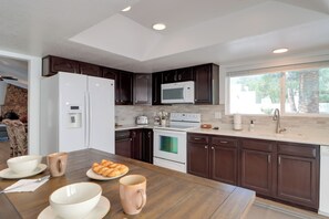 A modern kitchen with dark wood cabinets, white appliances, and a breakfast setup on the counter. - Extended Stay Gem: Tucson Townhome, Pool + Tennis (Tucson)