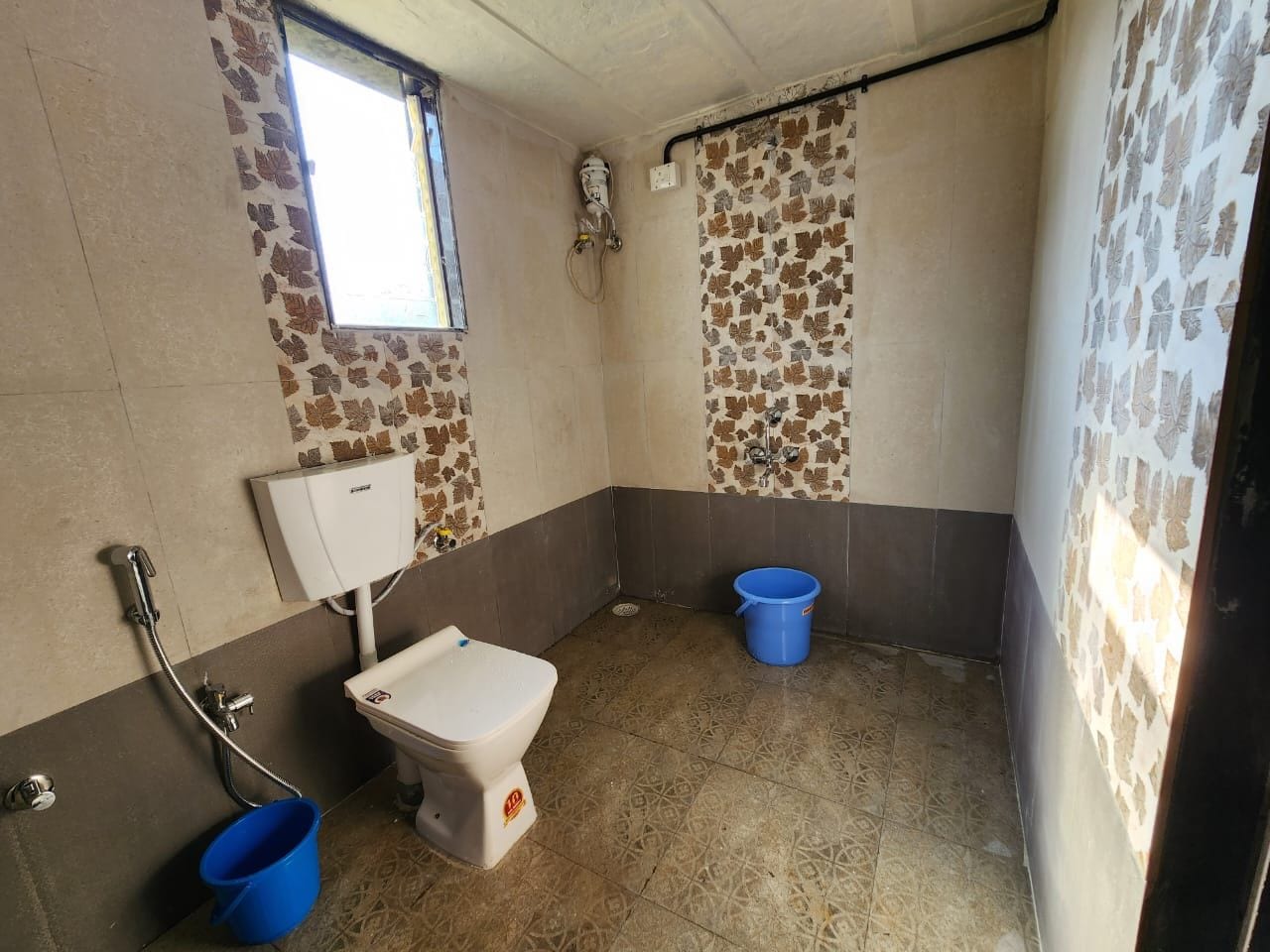 A bathroom with a toilet, a shower, and a blue bucket.