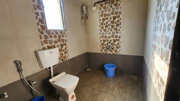 A bathroom with a toilet, a shower, and a blue bucket.