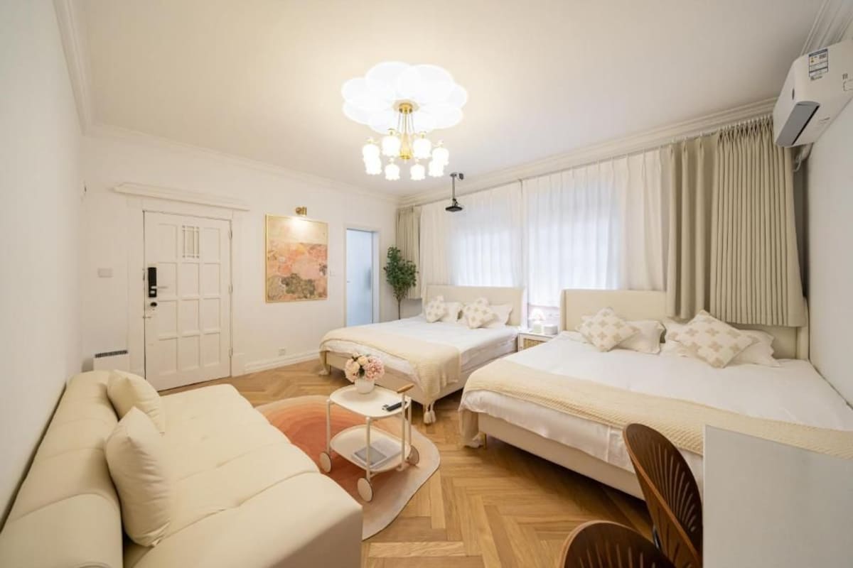 Een hotelkamer met twee bedden, een bank, een kleine tafel met een bloevas en een plafondlamp.