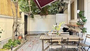 An outdoor patio with a wooden table and chairs, a red canopy, and potted plants. - Tonight Homestay West Nanjing Road SH (SHANGHAI)