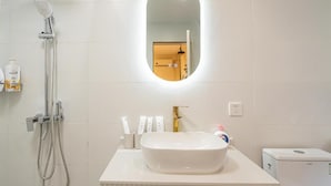 A bathroom with a white sink, a handheld showerhead, and a wall-mounted mirror. - Tonight Homestay West Nanjing Road SH (SHANGHAI)