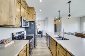 A modern kitchen with wooden cabinets, stainless steel appliances, and a large island with a sink. - Brand-New Build! Walkable Kremmling Retreat (Kremmling)