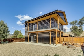 A two-story building with a balcony, a gravel driveway, and a wooden fence.