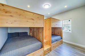 A room with bunk beds, wooden flooring, and a window.