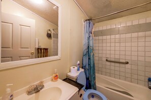 A bathroom with a toilet, sink, mirror, and shower curtain.