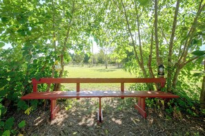 Eine hölzerne Bank in einem Park mit Bäumen und Rasen.