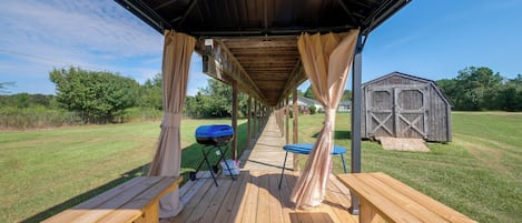 Un patio exterior techado con bancos de madera y una parrilla.