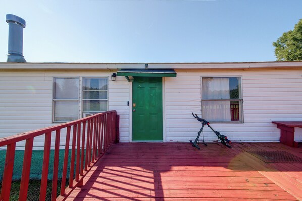 A single-story building with a green door, a red railing, and a bicycle parked outside.