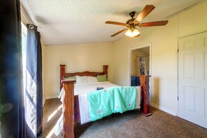 A bedroom with a wooden bed, a ceiling fan, and a door leading to another room.