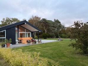 A modern house with a covered patio, a wooden deck, and a lawn. - 4 Star Holiday Home in Vejby (Vejby)