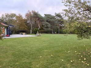 A well-maintained lawn with a gazebo, a covered seating area, and a building with a sloped roof. - 4 Star Holiday Home in Vejby (Vejby)