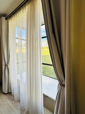 A room with a large window, curtains, and a view of a building and greenery outside. - Modern Fourways -Spacious 3Bedroom Retreat& 2 bath (Sandton)