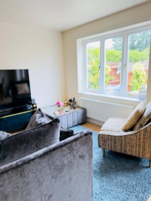 A living room with a sofa, a television, and a window with a view of greenery. - More photos to come in few weeks (Reedham)