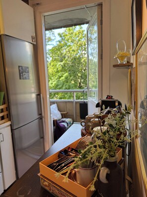 A kitchen with a refrigerator, a coffee maker, and a vase with flowers on the counter.