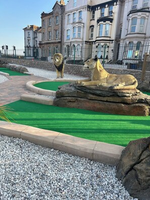 A landscaped area with a lion and a cheetah enclosure, surrounded by a stone wall and a building in the background. - 2 Bedroom Villa, Sleeps 5, WiFi, Parking, Beach (Dawlish Warren)