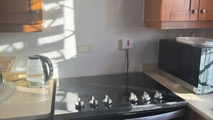 A kitchen with a stove, microwave, and cabinets. - At The Check-In Chill (Old Harbour)