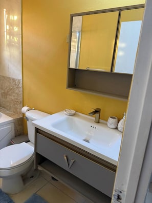 Un baño con inodoro blanco, lavamanos y espejo arriba.