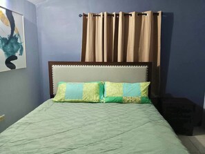 Una cama con cabecera, dos almohadas y una cortina color beige.