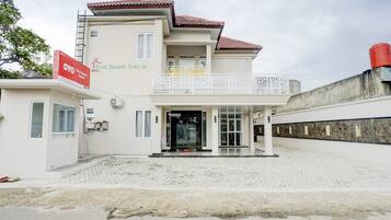 A two-story building with a balcony, a signboard, and a paved entrance area.