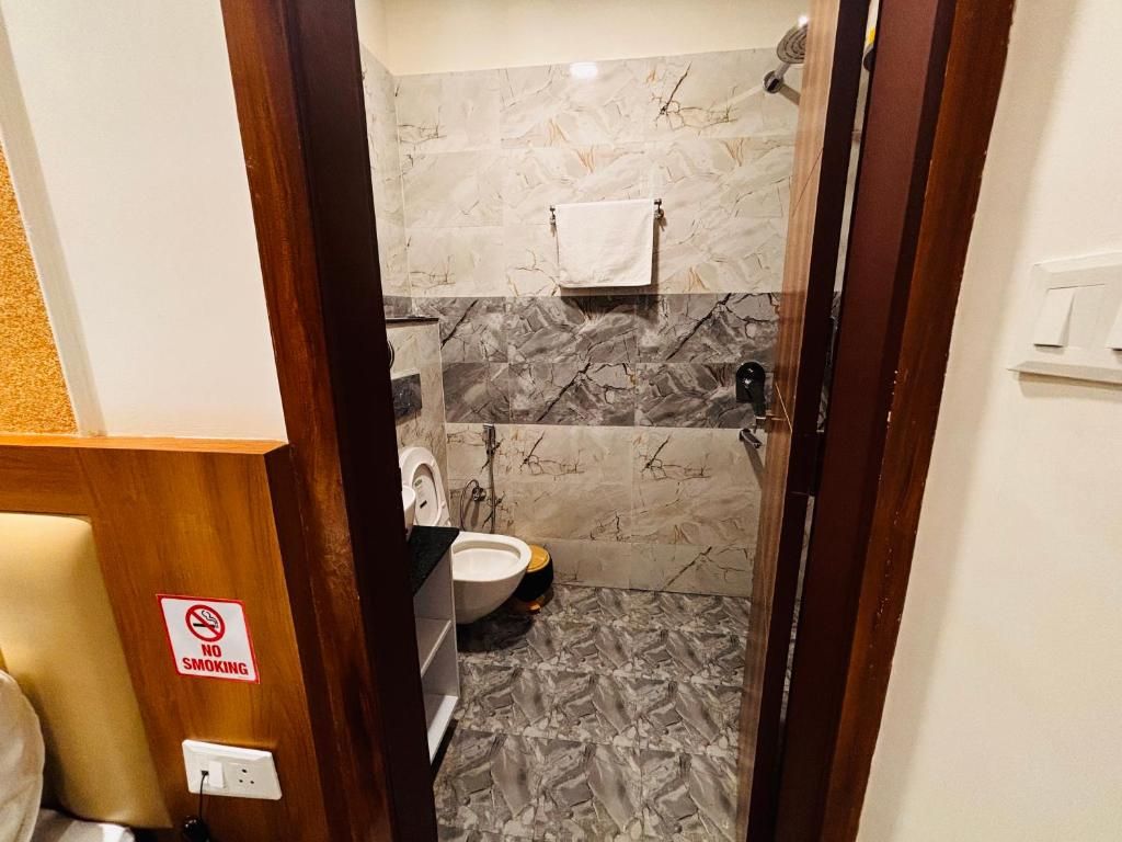 A bathroom with a marble floor, a toilet, a sink, and a shower area.