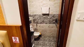 A bathroom with a marble floor, a toilet, a sink, and a shower area.