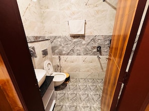 A bathroom with a toilet, sink, and shower area. - Hotel Shivay Palace (Rishikesh)