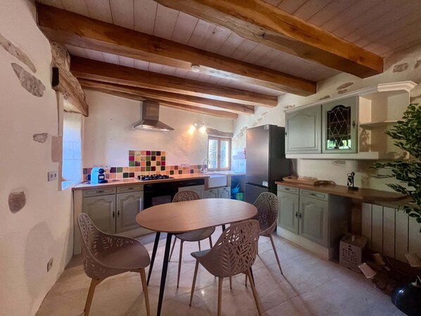 Eine Küche mit Holzboden, gefliestem Fliesenspiegel und einem Essbereich mit Tisch und Stühlen.