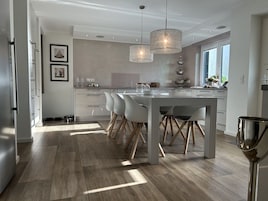 Una cocina moderna con una isla central, iluminación colgante y vistas al exterior.