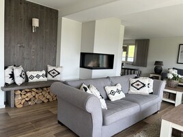 Una sala de estar moderna con un sofá gris, cojines estampados, un televisor de pantalla plana y una pared de madera.